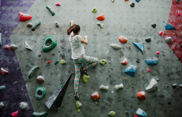 One young woman is enjoying rock climbing in a climbing centre.