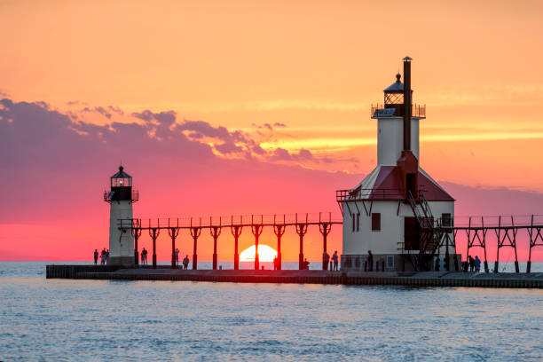 Solstice Sundown at St. Joseph Lighthouses On the Summer Solstice, the sun sets on Lake Michigan between the Inner and Outer North Pier Lighthouses at St. Joseph, Michigan. north pier stock pictures, royalty-free photos & images