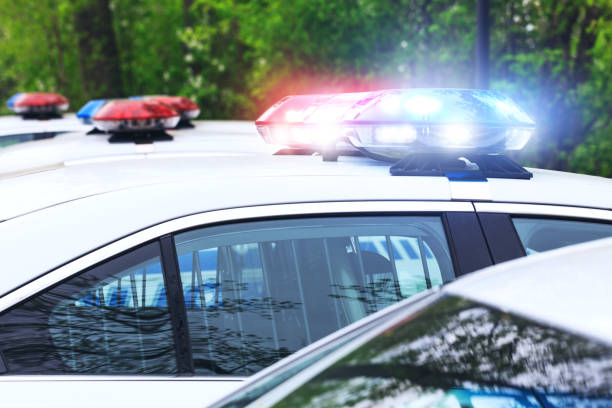 Some police cars with focus on siren lights. Beautiful siren lights activated on a police car before leaving the department park. Police cars stationed side by side, in full operation. stock photo