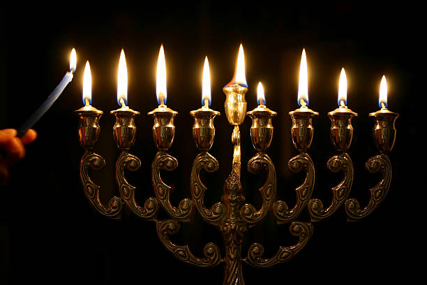Someone lighting the last candle of a Menorah stock photo