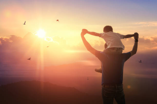 Son riding back father with outdoors on background sunset. Father holiday stock photo