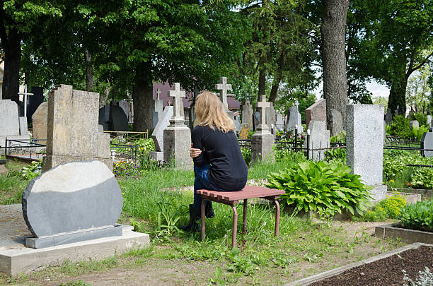 Sorrow woman shrinked near father husband grave stock photo