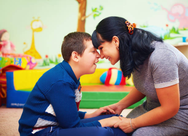 soulful moment. portrait of mother and her beloved son with disability in rehabilitation center stock photo
