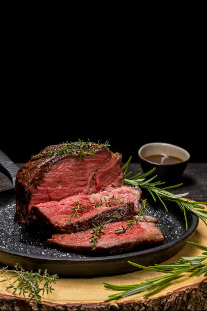 Sous-vide grilled beef steak with herbs in cast-iron skillet on wooden plate. stock photo