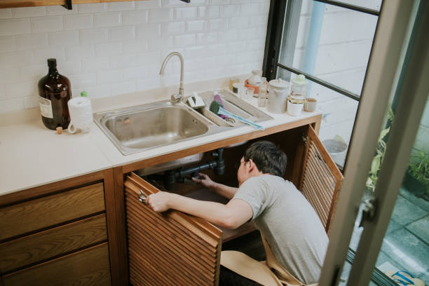 Southeast Asian repairman working in the kitchen stock photo
