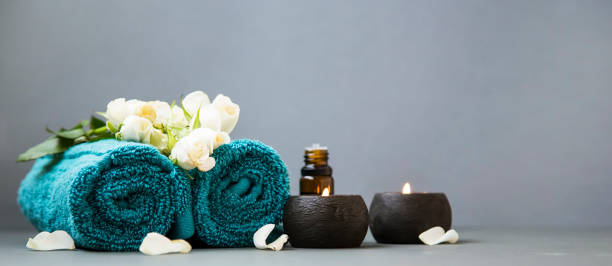 Spa still life with candles, towels and flowers on grey background copy space, spa and wellness still life stock photo