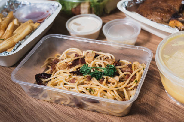 Spaghetti bacon chilli garlic on a table with other food Spaghetti bacon chilli garlic in a plastic box on a table with soup, french fries and other food. plastic container stock pictures, royalty-free photos & images