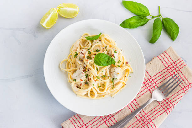 Spaghetti Pasta in White Sauce Garnished with Basil Leaves Directly Above Photo stock photo