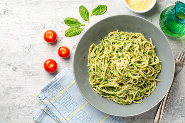 Spaghetti pasta with spinach sauce and parmesan cheese on concrete background stock photo