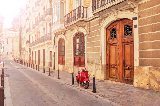 Spain. Valencia. A street in the tourist city of Valencia. Red motorcycle, moped. Tourist concept. Journey. Red vintage scooter parked on a sidewalk. stock photo