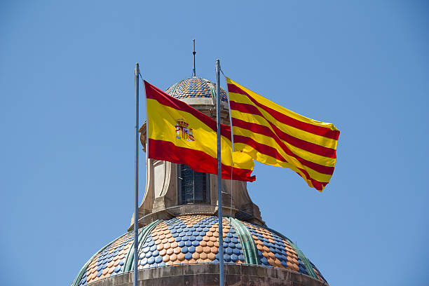 Spanish and Catalan Flag Spanish and Catalan flag flying together against blue sky on a bank building in Barcelona, Spain catalonia stock pictures, royalty-free photos & images