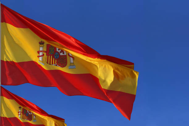 Spanish flags blowing in the wind   Cloudless azure sky stock photo
