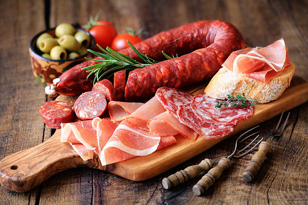Spanish meat tapas Cured meat platter of traditional Spanish tapas - chorizo, salsichon, jamon serrano, lomo - erved on wooden board with olives and bread sausage photos stock pictures, royalty-free photos & images