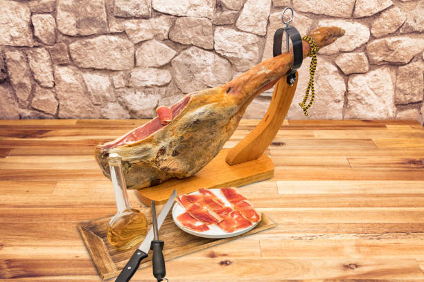 Spanish serrano ham on the leg with wood holder on a table stock photo