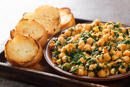 Spanish spinach and chickpeas served with toasts closeup in the plate on the table. Horizontal