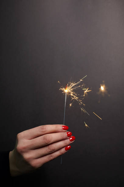 Sparkler in woman hand with red nail polish stock photo