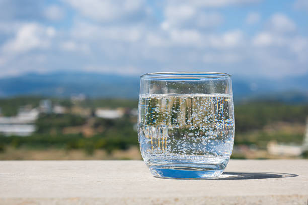 Sparkling water glass on a stone parapet with a mountain view. Cool glass of mineral water. Mountain mineral water. stock photo
