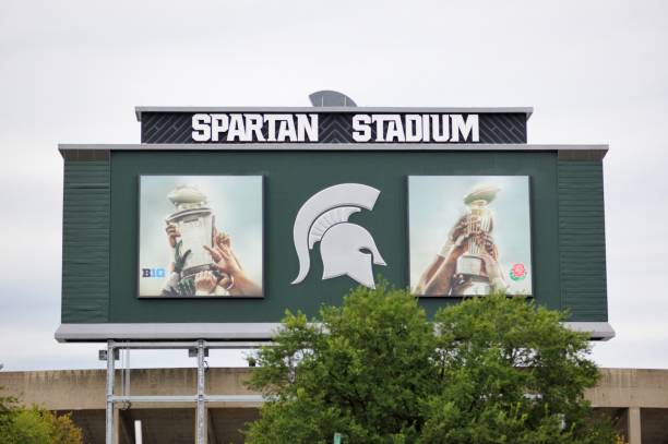 Spartan Stadium sign with championship trophy East Lansing, Michigan, USA - August 8, 2015: Sign on back of scoreboard at Spartan Stadium on the campus of Michigan State University in Lansing, Michigan. Image taken from the west side of the stadium on MSU campus. michigan football stock pictures, royalty-free photos & images