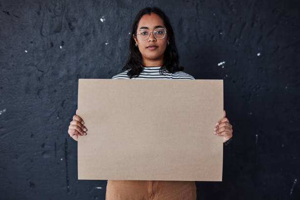 Speak your truth into existence Studio shot of a young woman holding a blank poster against a dark background me too social movement stock pictures, royalty-free photos & images