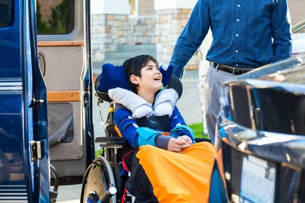 Special needs boy in wheelchair on vehicle handicap lift stock photo