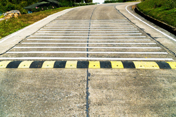 Speed bump road and rumble strip road background. Black and yellow speed bump line road and white rumble strip lines on concrete road surface Speed bump road and rumble strip road background. Black and yellow speed bump line road and white rumble strip lines on concrete road surface asien startblock stock pictures, royalty-free photos & images
