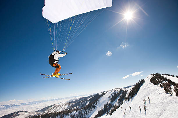 Speed Flyer Into The Sun Extreme sports. Action shot of a speed flyer zooming past, high above a mountain peak towards the sun. paragliding stock pictures, royalty-free photos & images