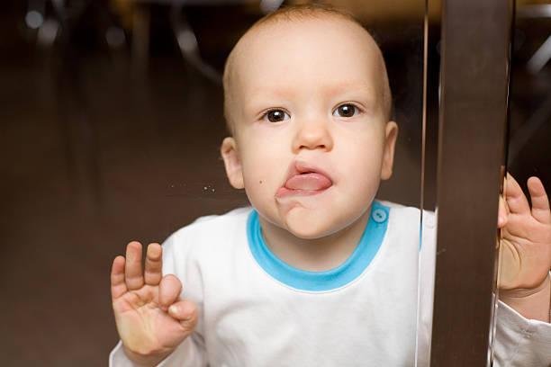 Spellbound baby cling by tongue to the shopwindow stock photo