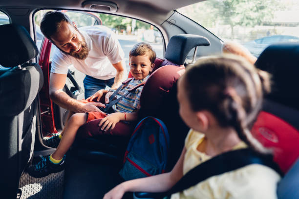 Spending the Day with Dad Father caring his kids to be safe during road trip car safety seat stock pictures, royalty-free photos & images