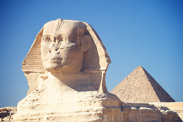 Sphinx with Great Pyramid Giza Egypt Blue Sky The Sphinx stands tall with the Great Pyramid in the distance in Giza Egypt under blue sky sphinx stock pictures, royalty-free photos & images