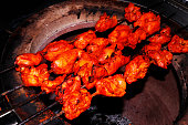 spice marinated chicken cubes ( chicken tikka )skewers cooking in a clay oven known as tandoor, indian food