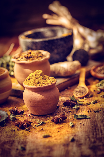 Variation of Spices and Herbs like chili peppers, ginger, garlic, rosemary, sage, peppercorns, star anise, cardamon, cayenne pepper, tumeric, cumin, fennel seeds on wooden background