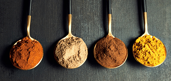 Spices, food and seasoning for luxury cooking at a restaurant kitchen making spicy, aromatic and tasty Asian or Indian meal. Colorful different dry ground powder consumables on a black background