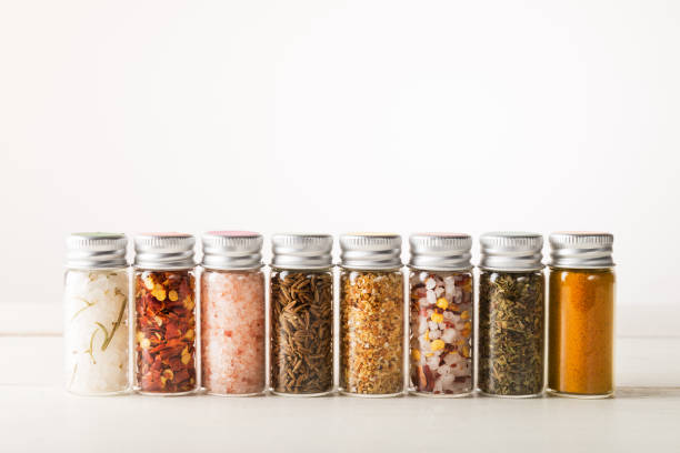 Spices Set in Mini Bottles Spices Set in Mini Bottles, such as basil, turmeric, salts, chilli flakes, cumin seeds on light background spice stock pictures, royalty-free photos & images