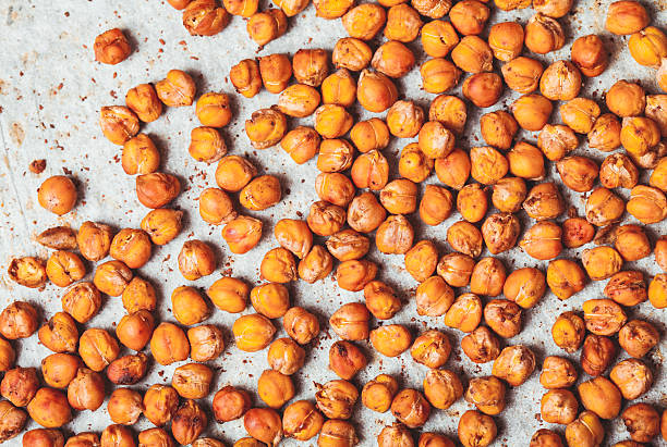 Spicy baked chickpeas Spicy baked chickpeas scattered on  baking paper chick pea stock pictures, royalty-free photos & images