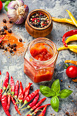Spicy hot chili sauce with of chilli pepperSpicy hot chili sauce with of chilli pepperChili peppers and chili sauce.Hot sauce from chilli peppers and tomatoes on wood background