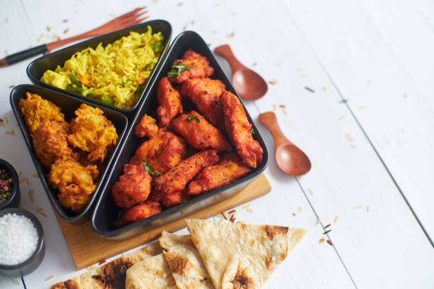 Spicy indian fried chicken served with curry vegetable rice, onion bhajia, naan bread stock photo