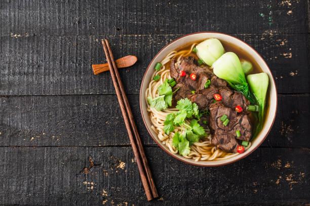 Spicy red soup beef noodle in a bowl on wooden table stock photo