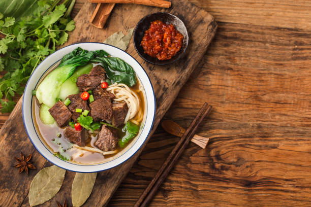 Spicy red soup beef noodle in a bowl on wooden table stock photo