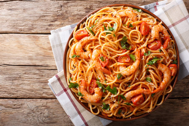 Spicy spaghetti with shrimps in tomato sauce close-up. Horizontal top view from above Spicy spaghetti with shrimps in tomato sauce close-up on a plate. horizontal top view from above prawn seafood stock pictures, royalty-free photos & images