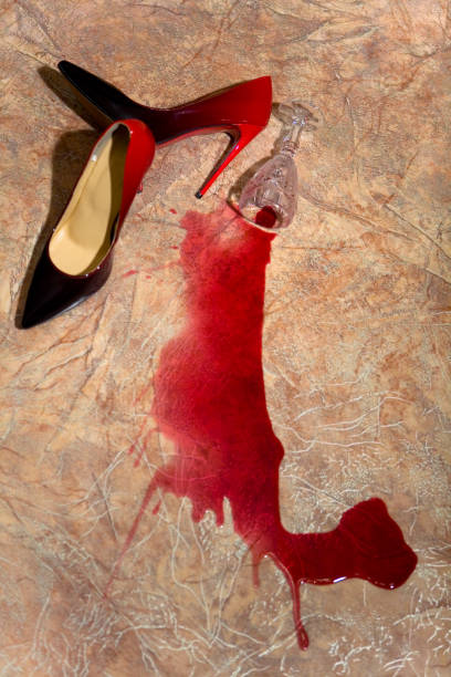 A spilled glass of wine and women's shoes on the floor. stock photo