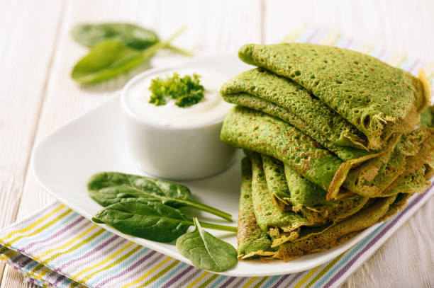 Spinach green pancakes (crepes) with sour cream. stock photo