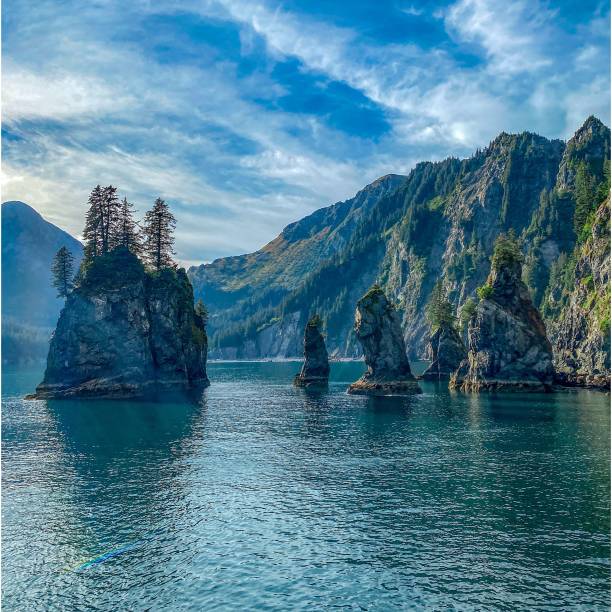 Spire Cove Calm Turquoise Water of Spire Cove in the Kenai Fjords National Park on A Sunny Day with A Blue Sky and Soft White Clouds in Alaska kenai peninsula stock pictures, royalty-free photos & images
