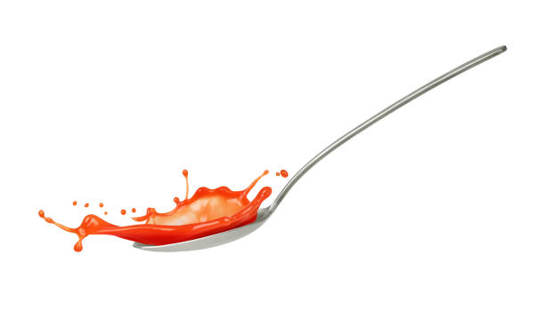 splash of ketchup in spoon on white background stock photo