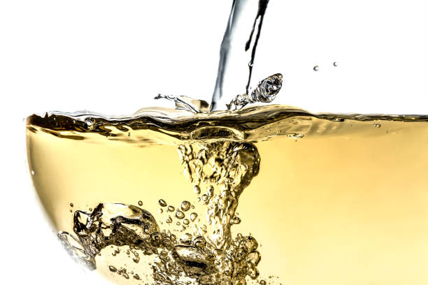 Splash white wine in glass with bubbles close-up macro texture isolated on top on white background. Wave of white wine with beautiful fizz. stock photo