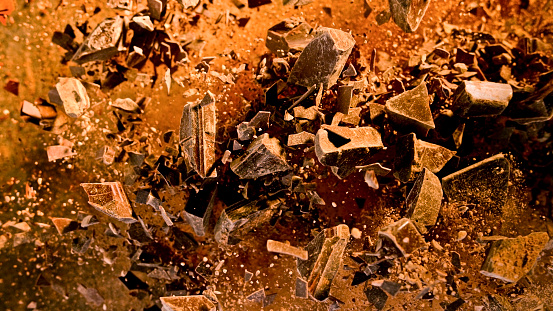 Close-up of splashing chocolate powder against black background.