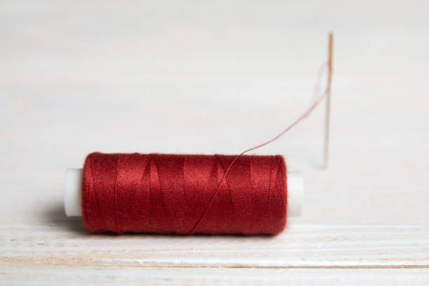 A spool of red thread and a needle. stock photo