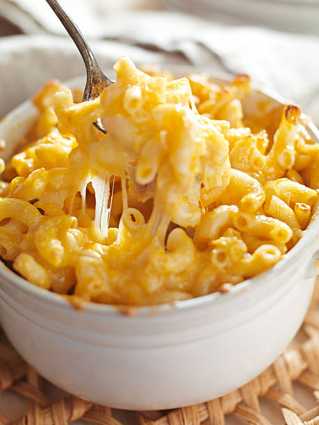 spoon in a bowl of macaroni and cheese - gebakken in de oven stockfoto's en -beelden