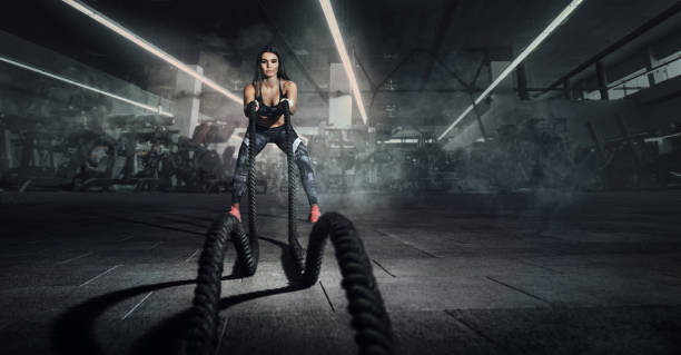 Sport. Battle ropes session. Attractive young fit sportswoman working out in functional training gym doing exercise with battle ropes. Sport backgrounds. manufactured object stock pictures, royalty-free photos & images