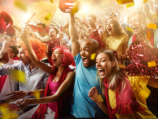 Sport fans: Group of cheering fans :biggrin:On the foreground a group of cheering fans watch a sport championship on stadium. Everybody are happy. People are dressed in casual cloth. Colourful confetti flies int the air. cheering stock pictures, royalty-free photos & images
