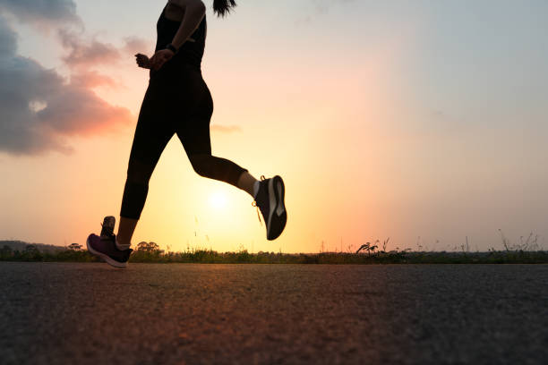 sport woman running on a road. Fitness woman training at sunset sport woman running on a road. Fitness woman training at sunset asian girls feet stock pictures, royalty-free photos & images